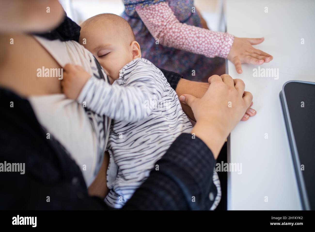 Sleeping baby peacefully resting in arms and holding the shirt of her