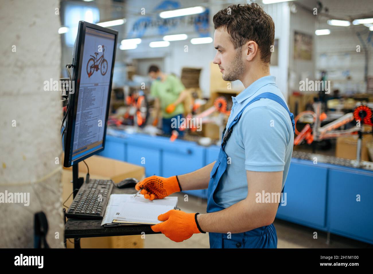 Bicycle factory, worker manages bike assembly line. Male mechanic in