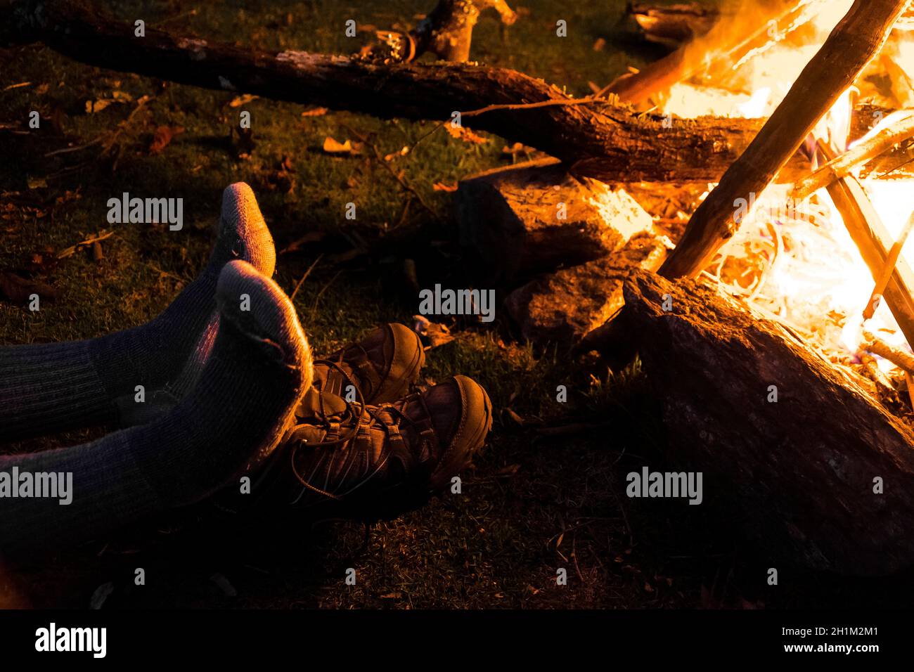 Wet feet in socks drying over a bonfire at a camping site Stock Photo