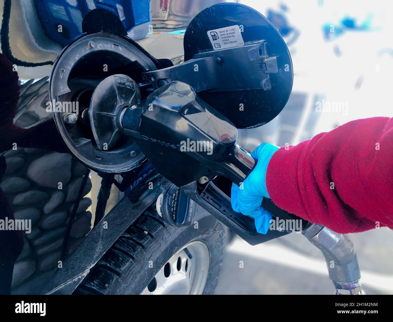 Calgary, Alberta, Canada. Nov 15, 2020. A person wearing single use gloves, pumping gasoline to a chevrolet SUV vehicle during the pandemic covid-19 c Stock Photo