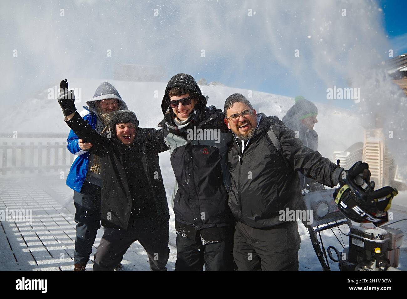 Les Orres, France - Circa 2015: Happy skiers posing for group photos while someone blasting snow on them using snow plowing machine to clear the terra Stock Photo