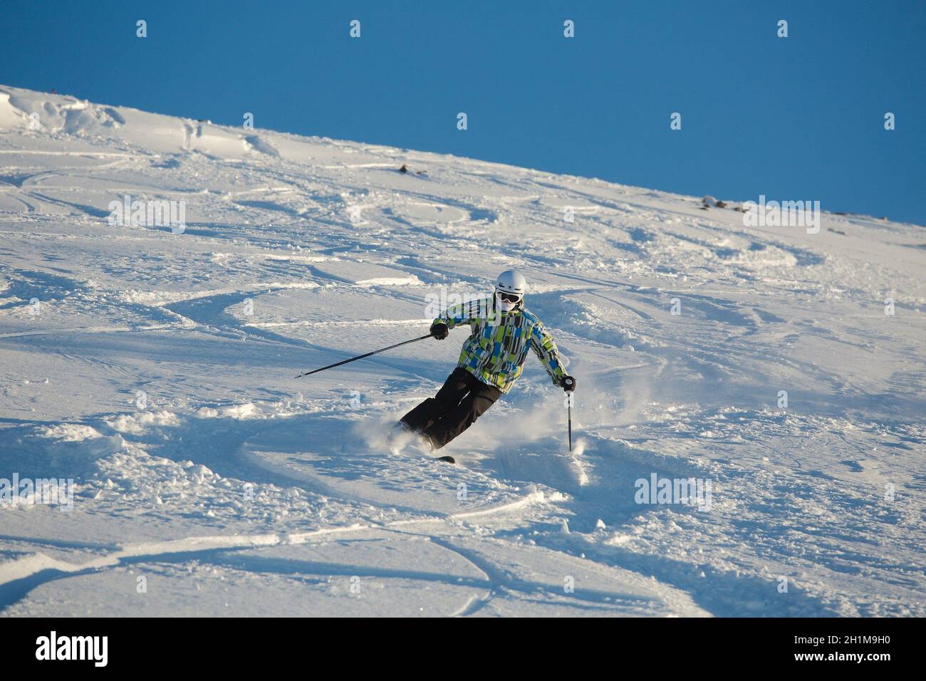 Les Orres, France - Circa 2015: Young skier coming down fast in fresh powder snow off-piste. Stock Photo