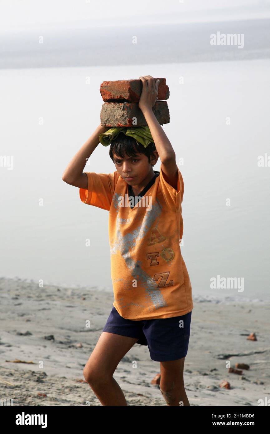 Child workers carry bricks carrying it on his head in Sonakhali, West Bengal, India Stock Photo