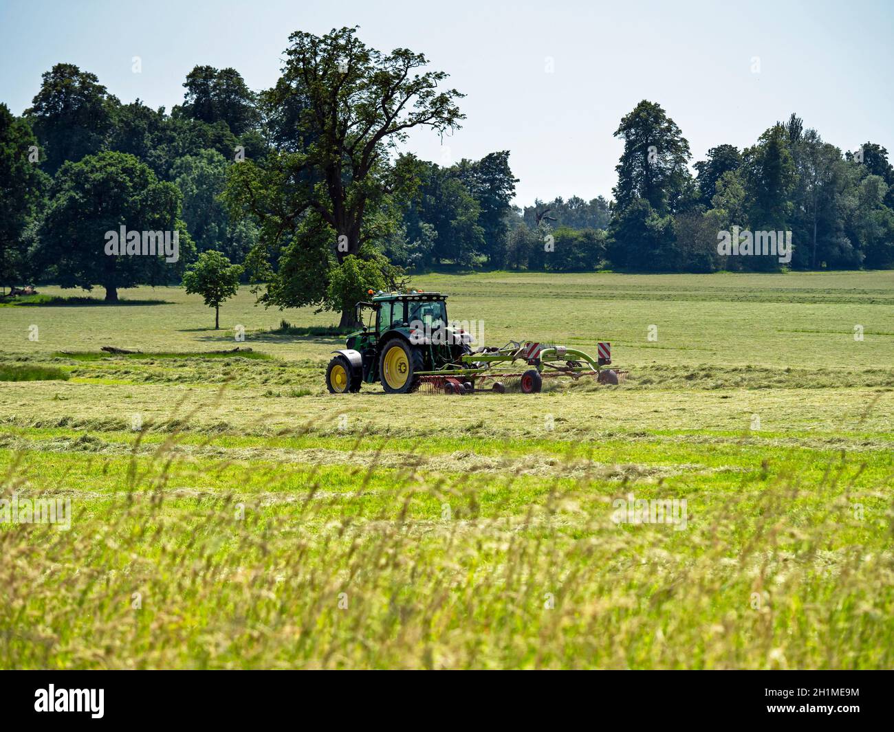 Tractor mowing grass in a large field on a country estate with