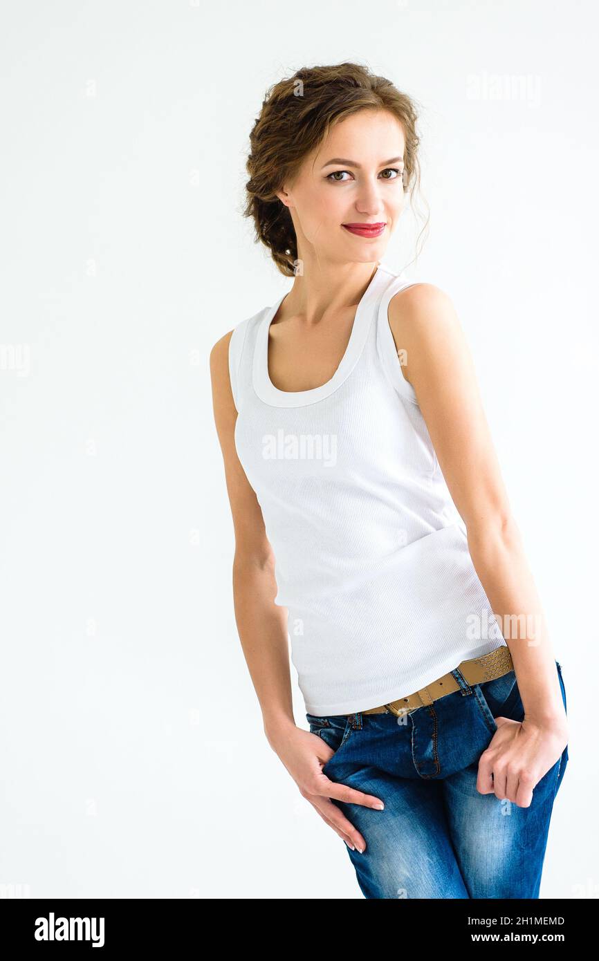 cheerful girl in a white t-shirt and dark blue jeans in the studio on a white background stands, sits, runs Stock Photo