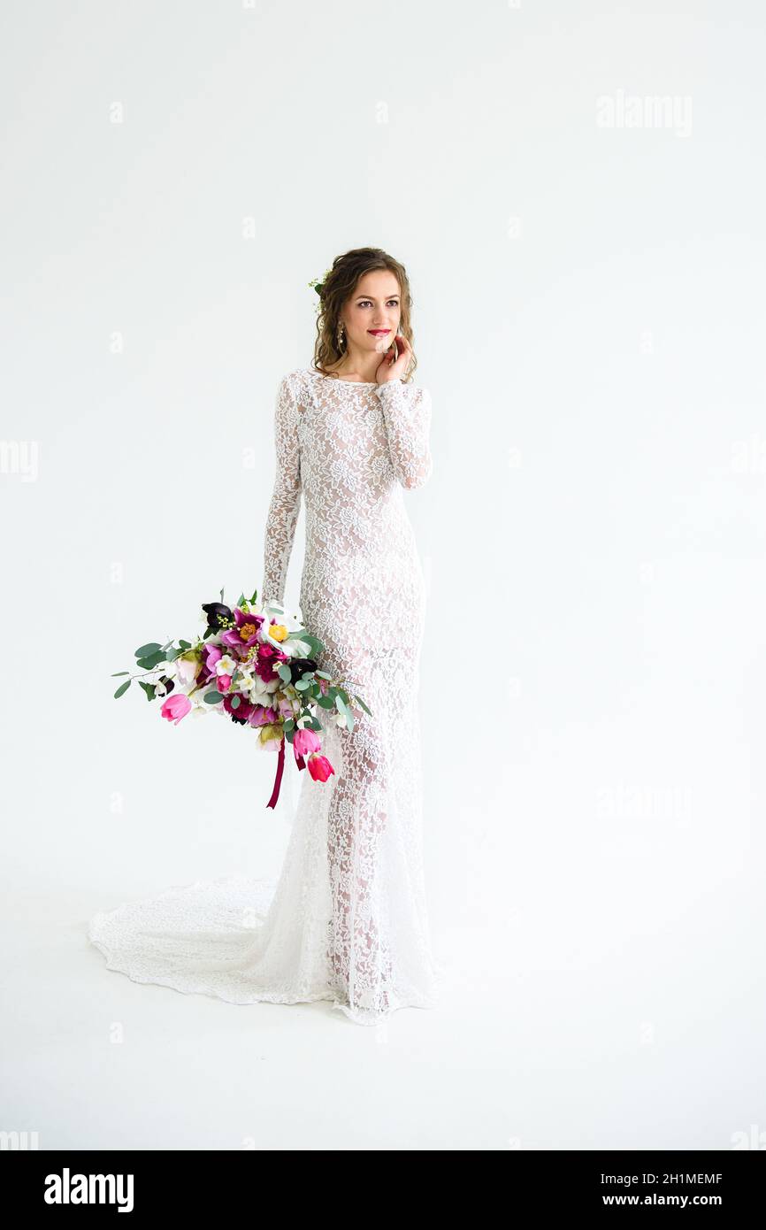 joyful girl bride in a white knitted dress posing with a bouquet of ...
