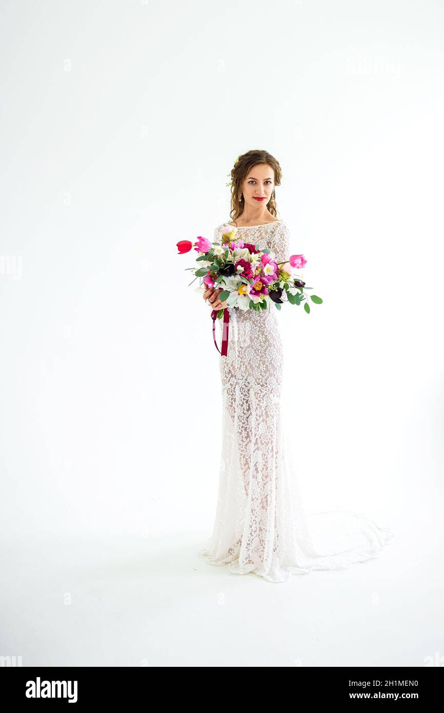joyful girl bride in a white knitted dress posing with a bouquet of ...