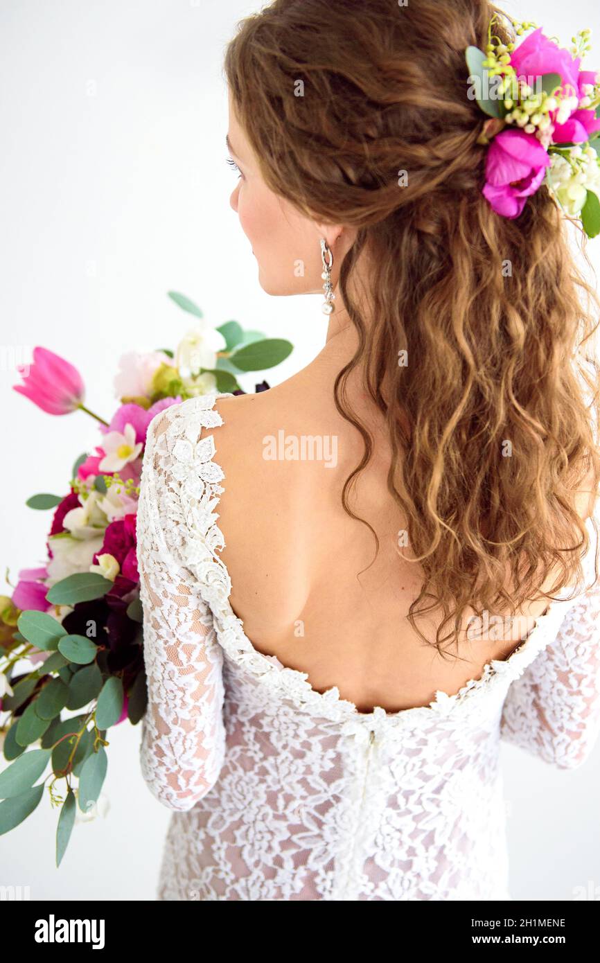 joyful girl bride in a white knitted dress posing with a bouquet of ...