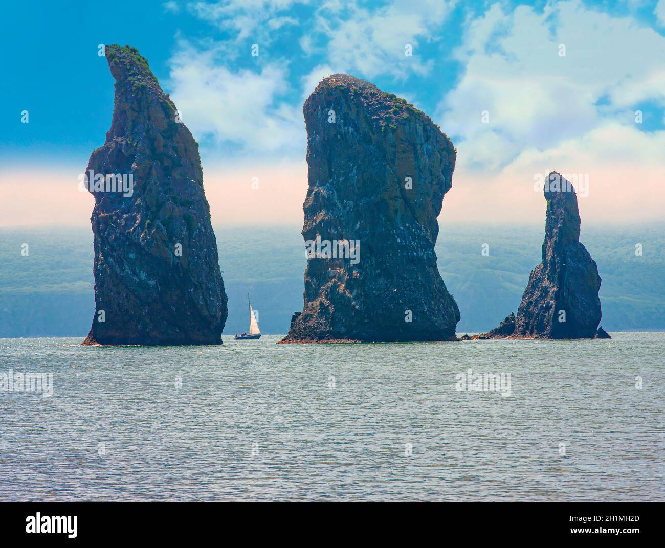The Sailboat sails near the coast and rocks on Kamchatka Peninsula Stock Photo
