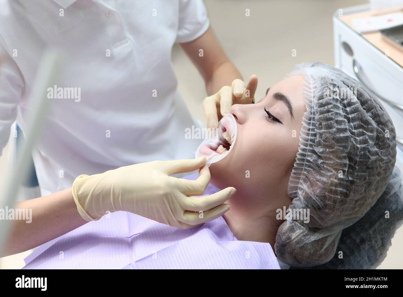 A young girl at a dentist appointment. The doctor inserts the retractor ...