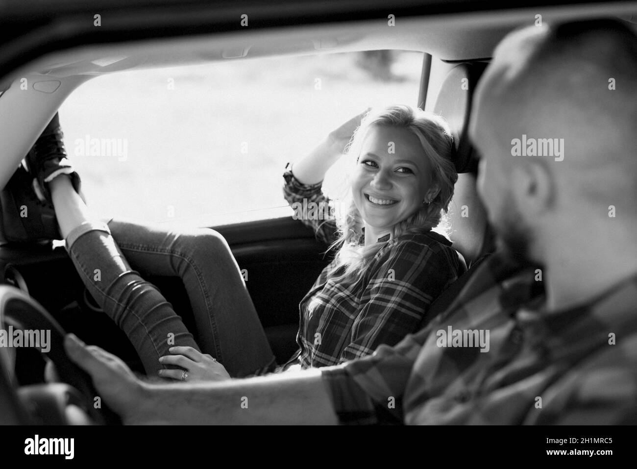 traveling by car of a young couple of a guy and a girl in plaid shirts Stock Photo
