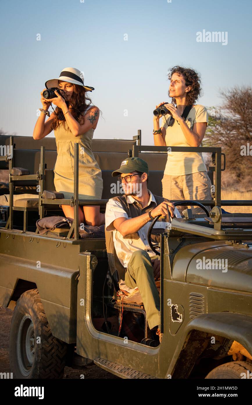 Brunettes use camera and binoculars in jeep Stock Photo