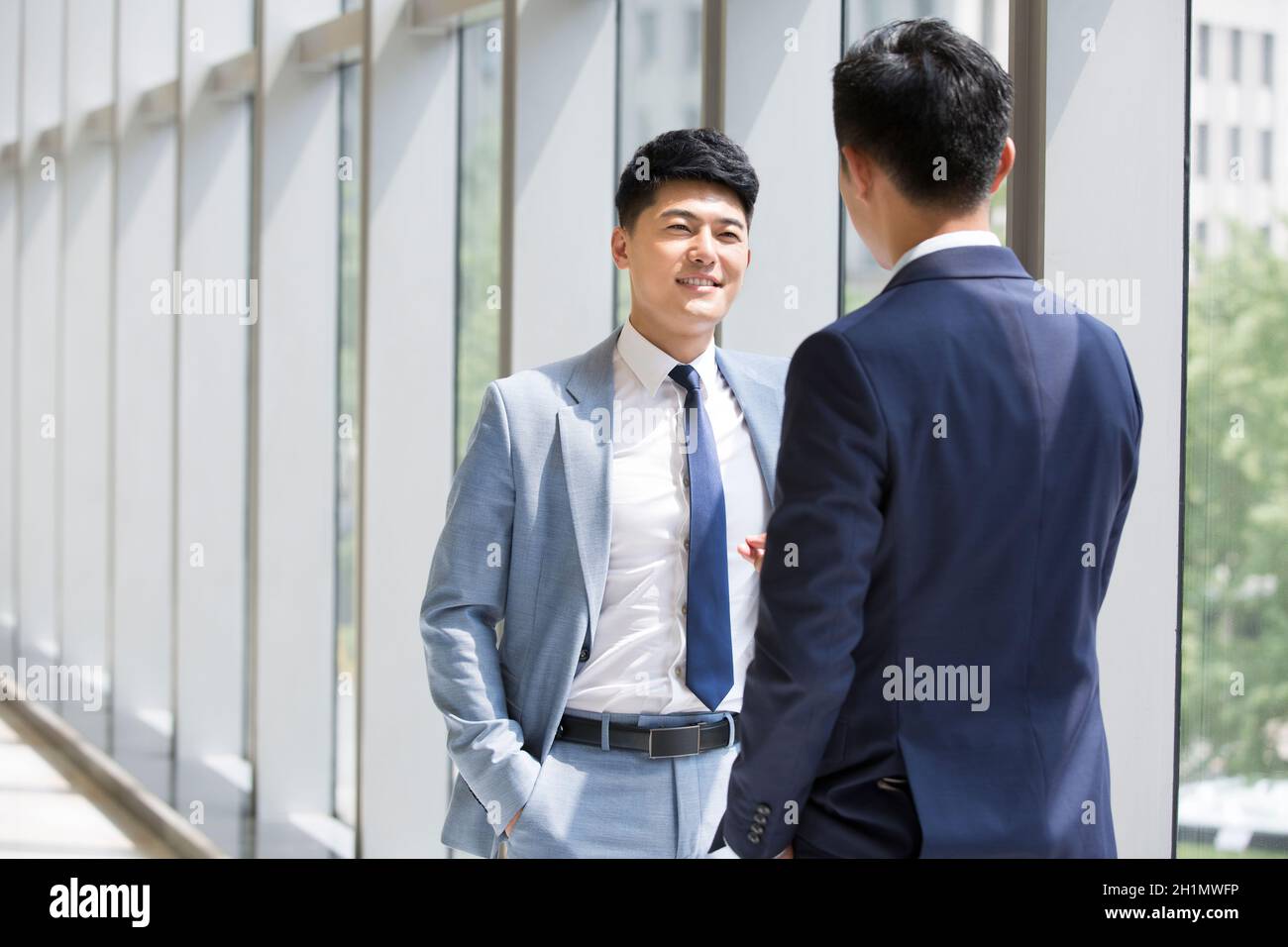 Businessmen talking by the window Stock Photo - Alamy
