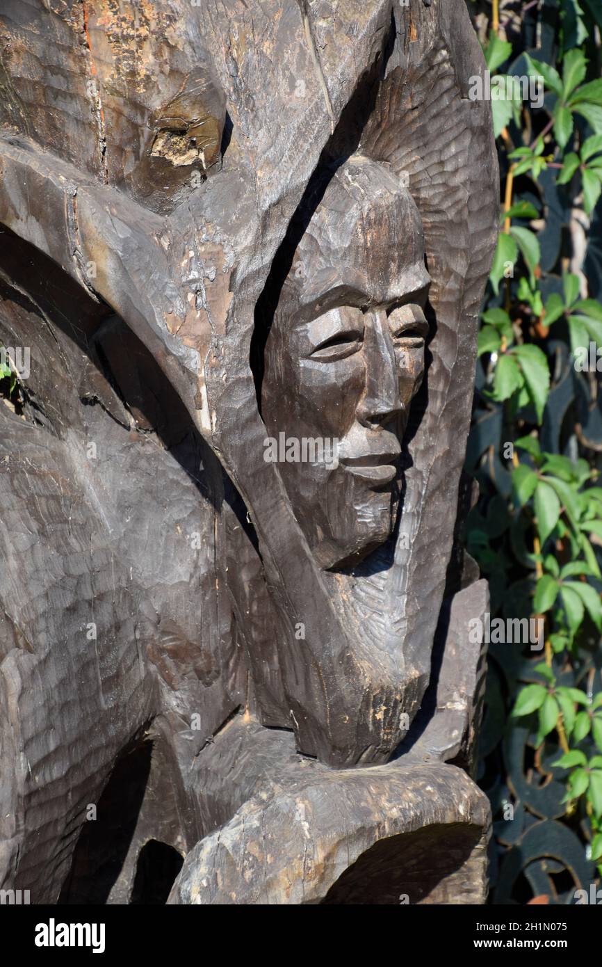 Wooden idol. Woodcarving. Man's face is carved on the trunk of a log Stock Photo