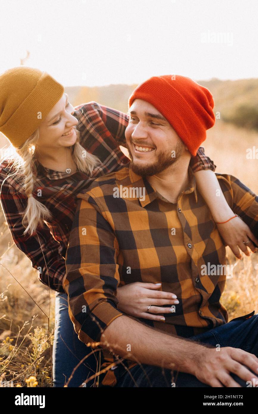 Cheerful guy and girl on a walk in bright knitted hats and plaid shirts Stock Photo