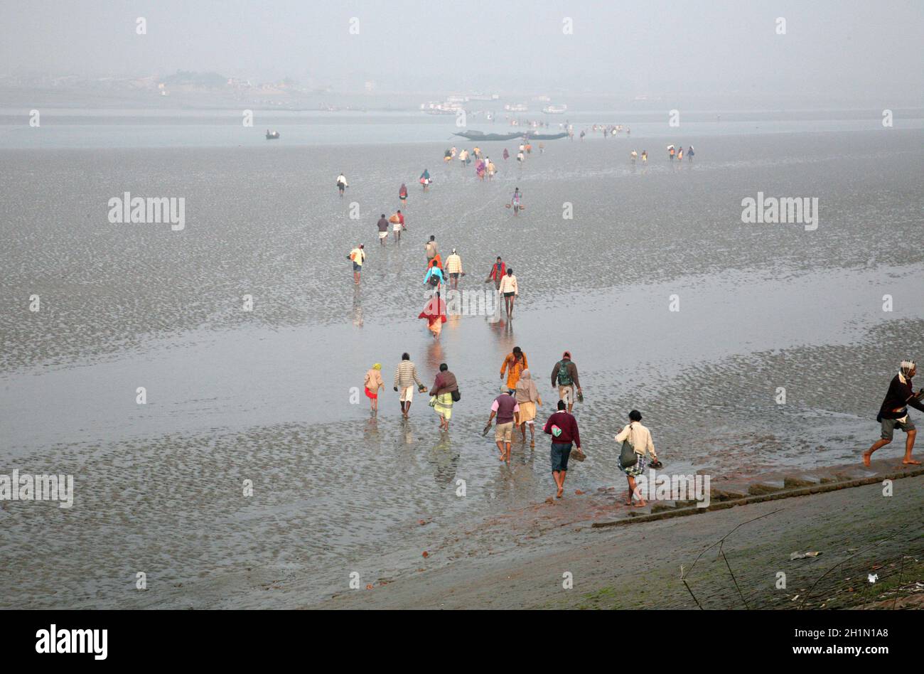 During low tide the water in the river Matla falls so low that people walk to the other shore in Canning Town, India Stock Photo