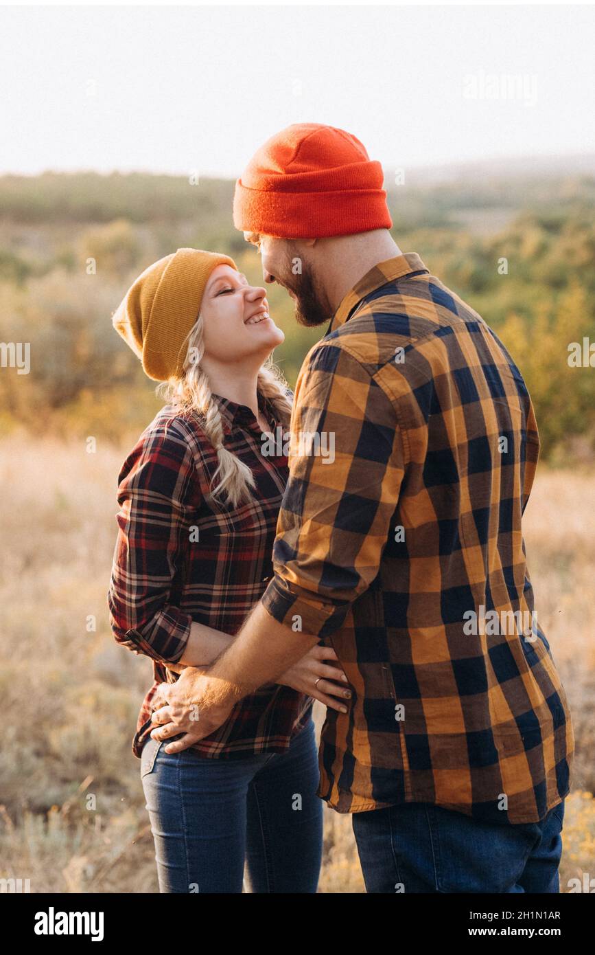 Cheerful guy and girl on a walk in bright knitted hats and plaid shirts Stock Photo