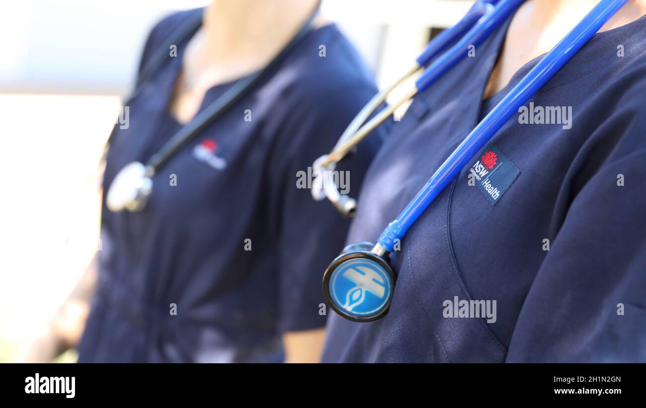 The NSW Government Health logo or emblem with waratah in focus on a nurse or doctors navy blue uniform. Stethoscope in focus. Illustrative editorial Stock Photo