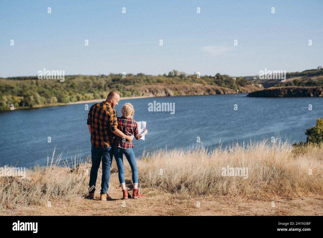 Bald guy with a beard and a blonde girl are looking at the map and looking for a route to travel Stock Photo