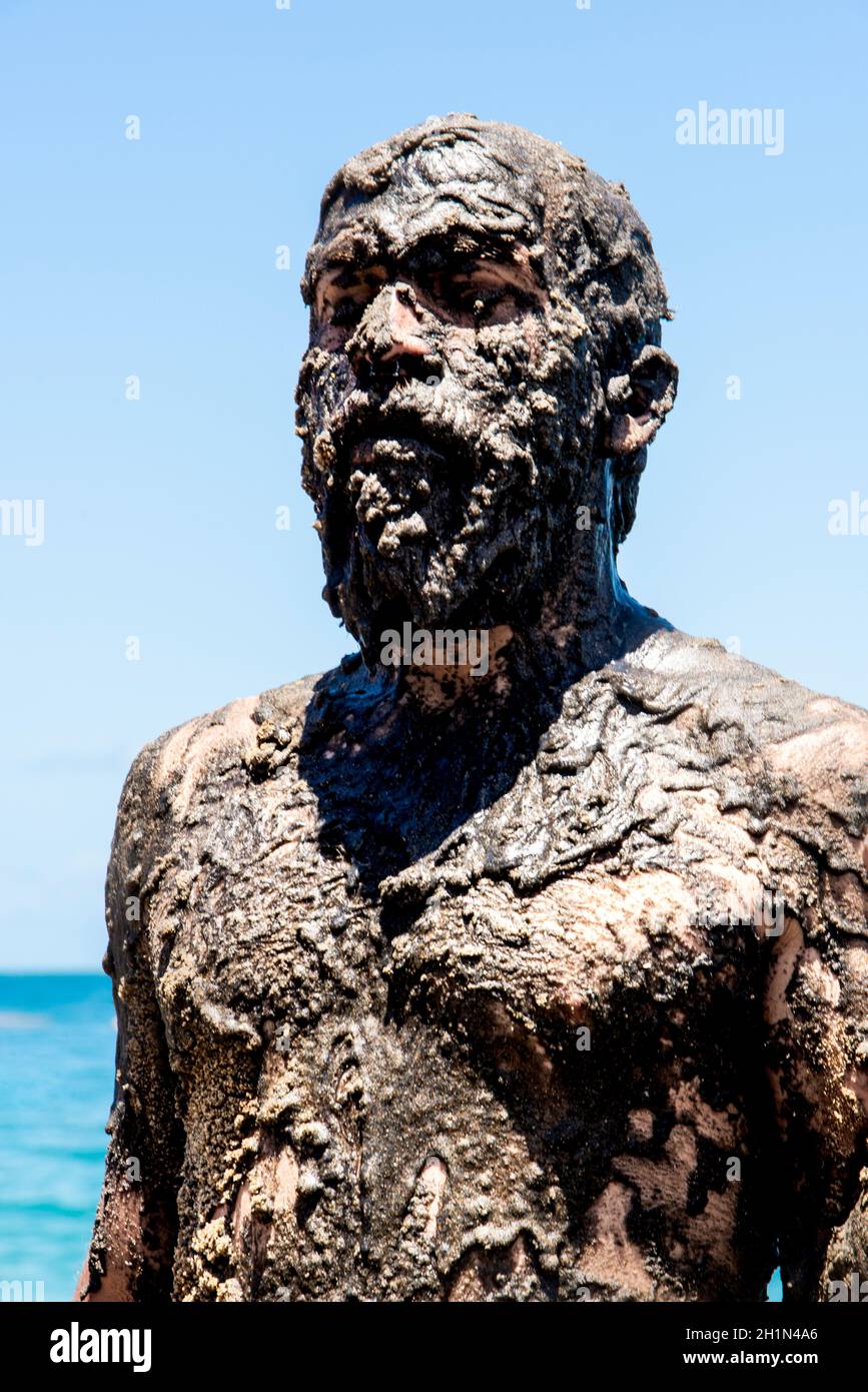 Man covered in oil on the beach at Porto da Barra in Salvador, Bahia, in protest of oil spilled by a ship on the beaches of Brazil. Stock Photo