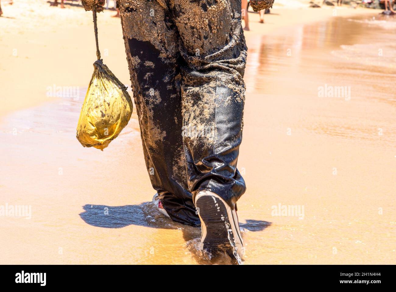 Man covered in oil on the beach at Porto da Barra in Salvador, Bahia, in protest of oil spilled by a ship on the beaches of Brazil. Stock Photo