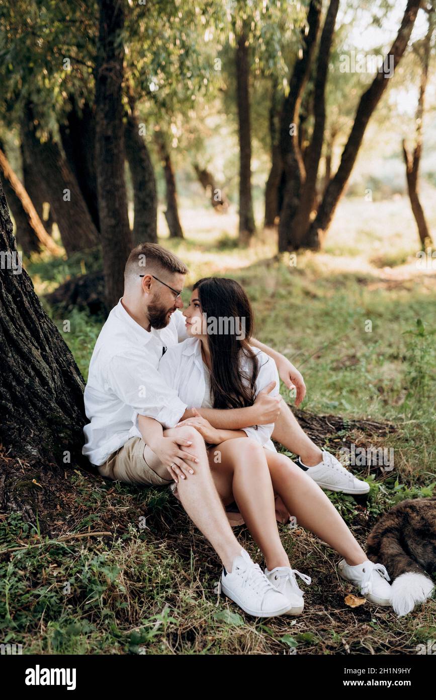 young couple in love a guy with a beard and a girl with dark hair in light clothes in the green forest Stock Photo