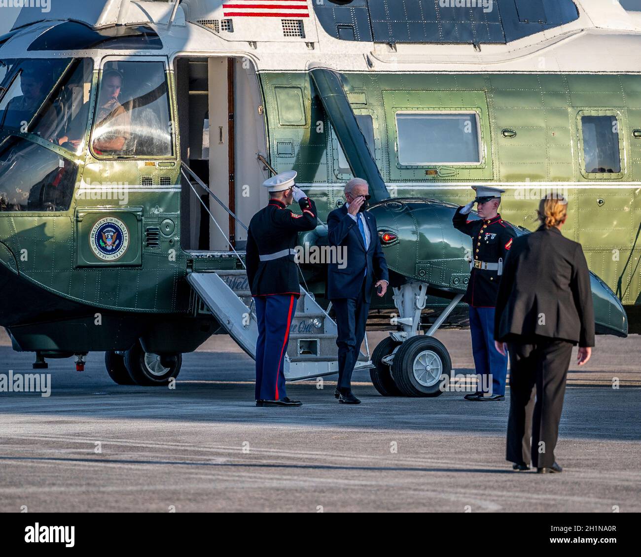 President Joe Biden salutes a pair of Marines as he disembarks from