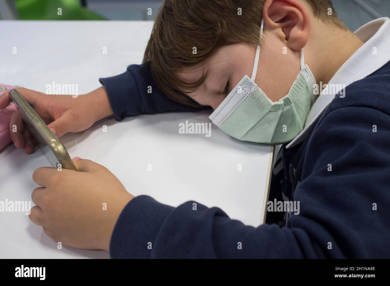 Tired 5 years old sleeping while he holds smartphone. Too much screen time concept Stock Photo