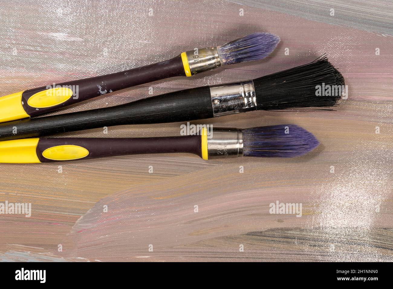 Brushes for painting  lying on an old canvas painted with oil paints Stock Photo
