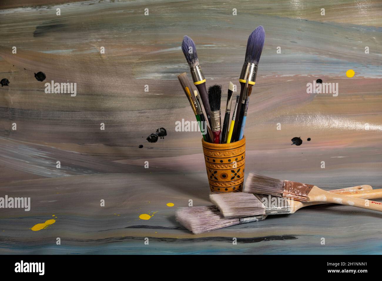 Brushes for painting in a wooden pencil case lying on an old canvas painted with oil paints Stock Photo