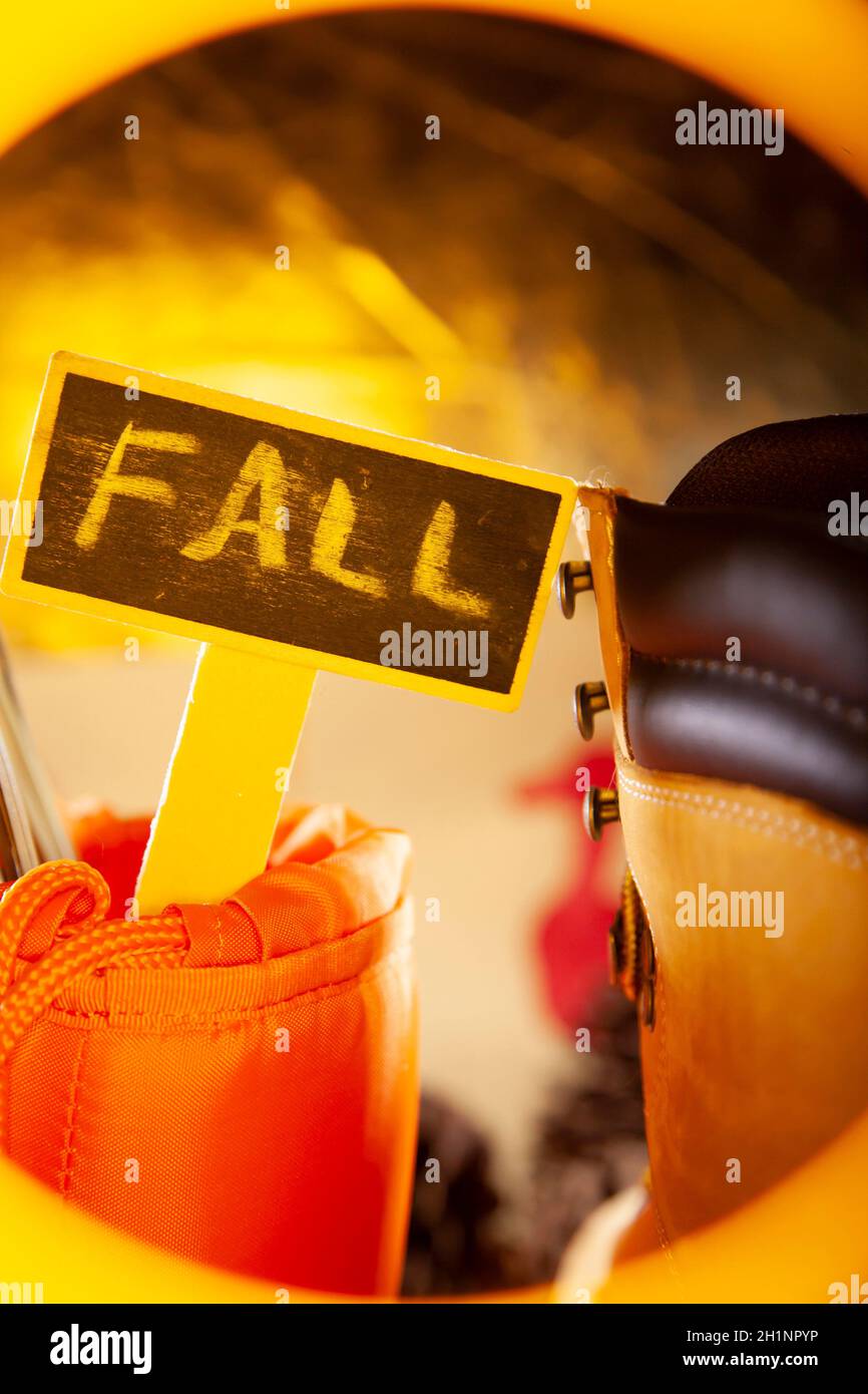 'FALL' sign in a hunter orange carrying pouch next to a boot, with a golden tone Stock Photo