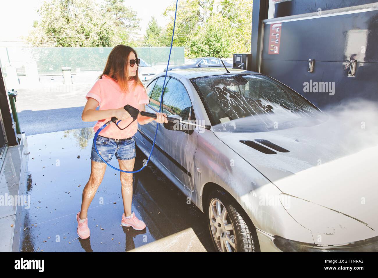 Pretty Woman Washing Her Car With High Pressure Washer At SelfServe