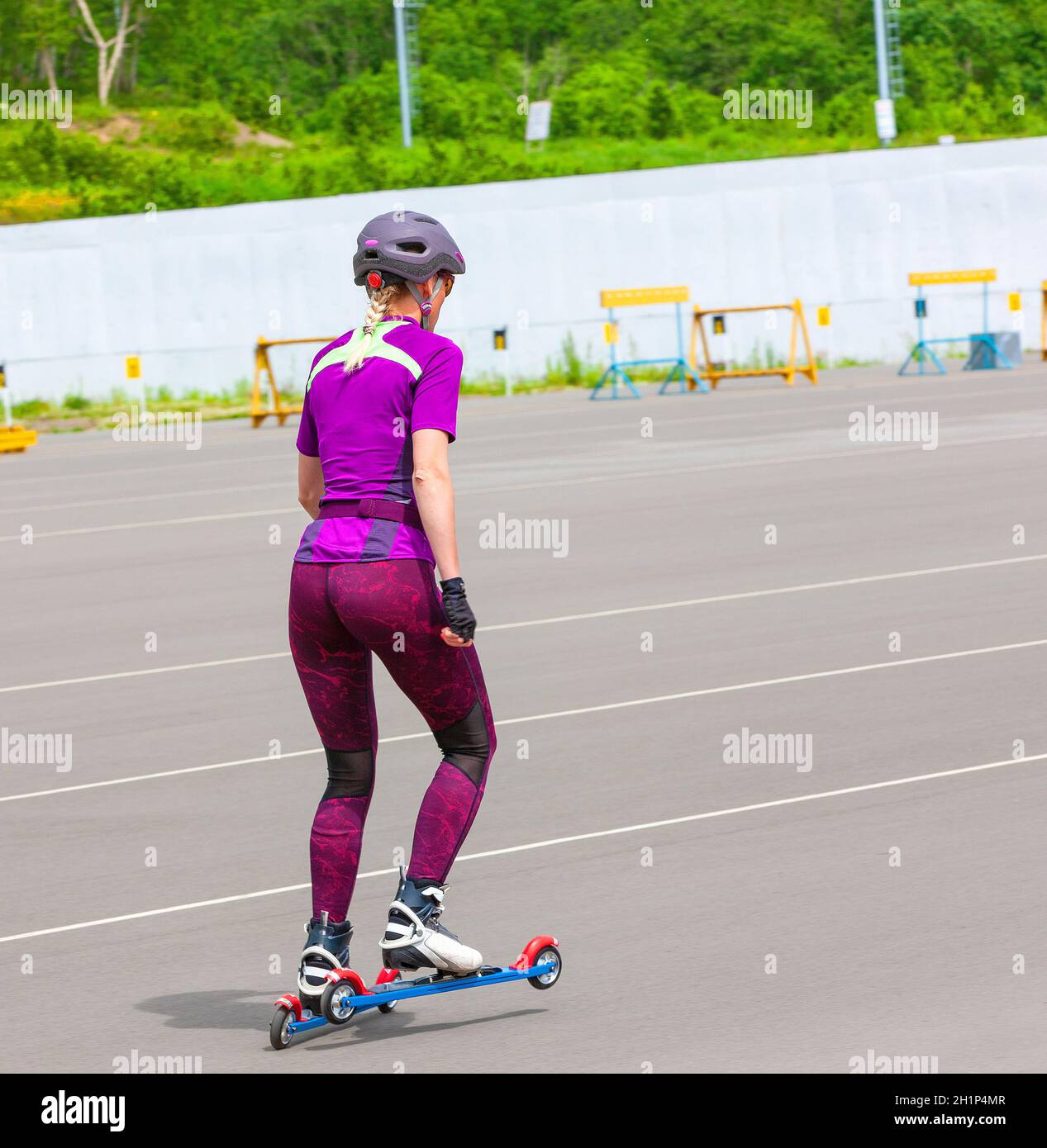 The girl sportswoman rides on the roller skis on the asphalt Stock Photo