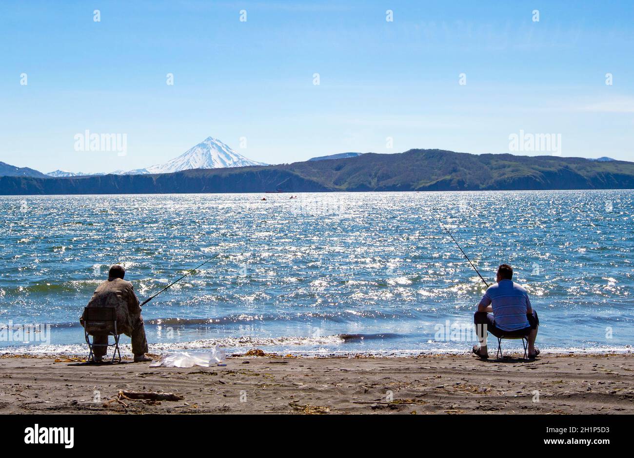 Fisherman sitting and fishing on the beach of Pacific ocean Stock Photo