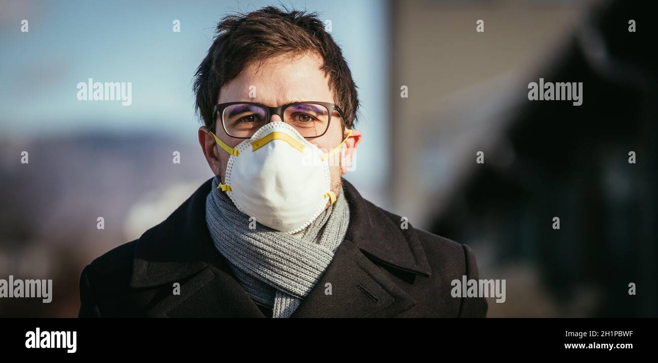 Young man outdoors with a breathing mask. Flue and corona season Stock Photo