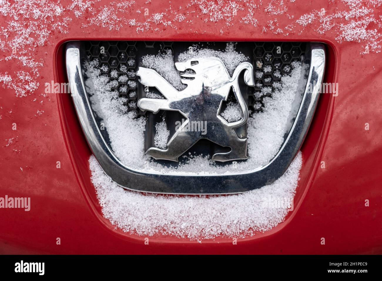 BERLIN - JANUARY 16, 2021: Silver Peugeot emblem on the hood of the car covered with snow. Stock Photo