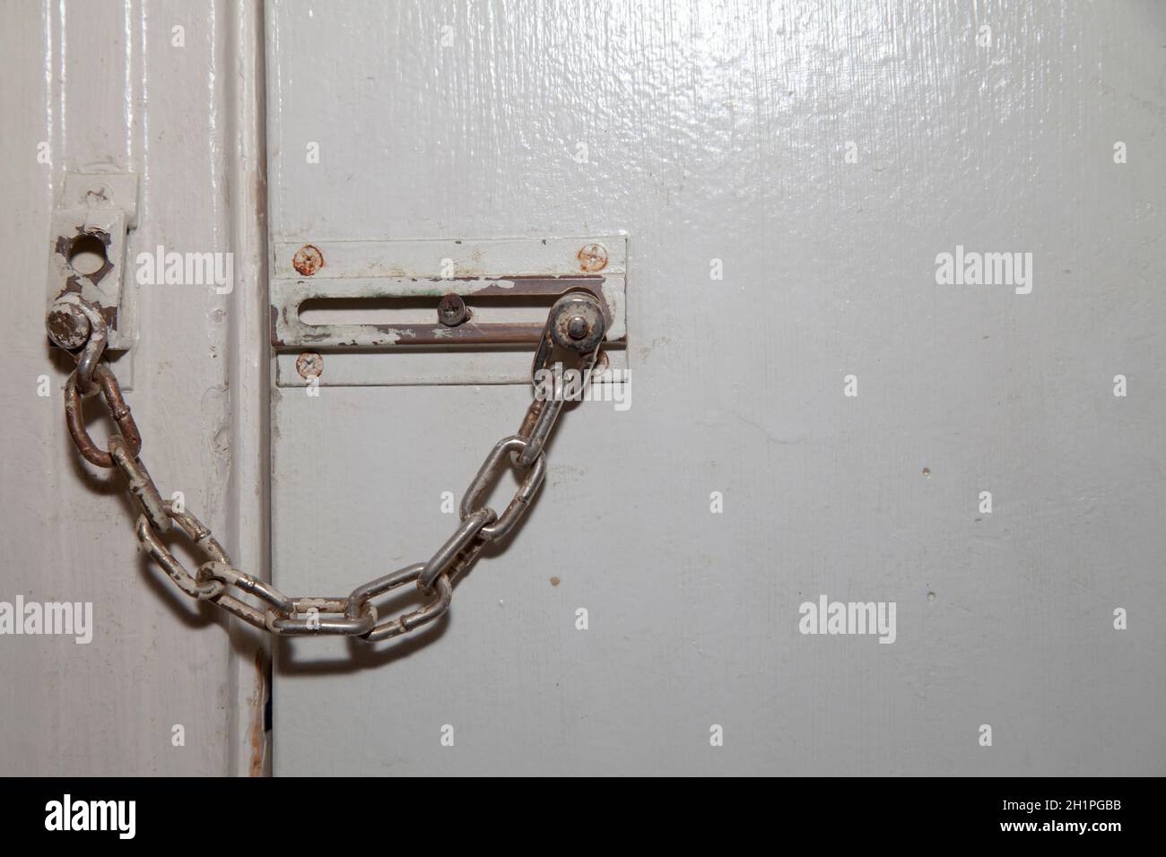 Old door chain not in the locked position on a white door Stock Photo