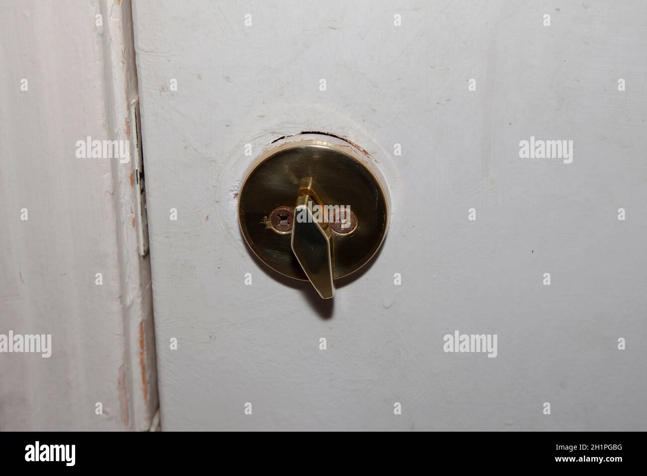 Deadbolt on an old white door not locked Stock Photo