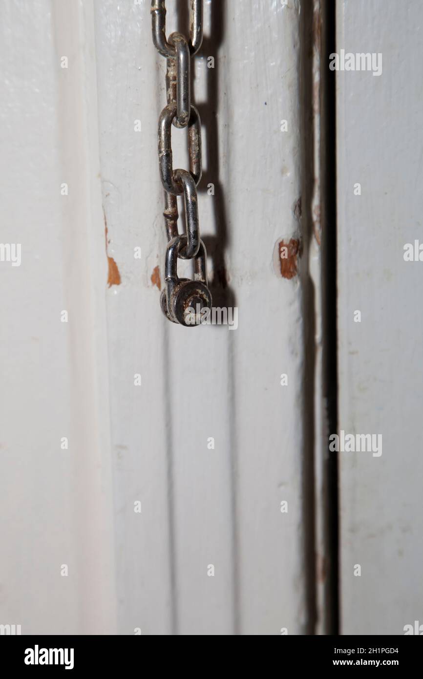 Old door chain hanging on a door frame Stock Photo