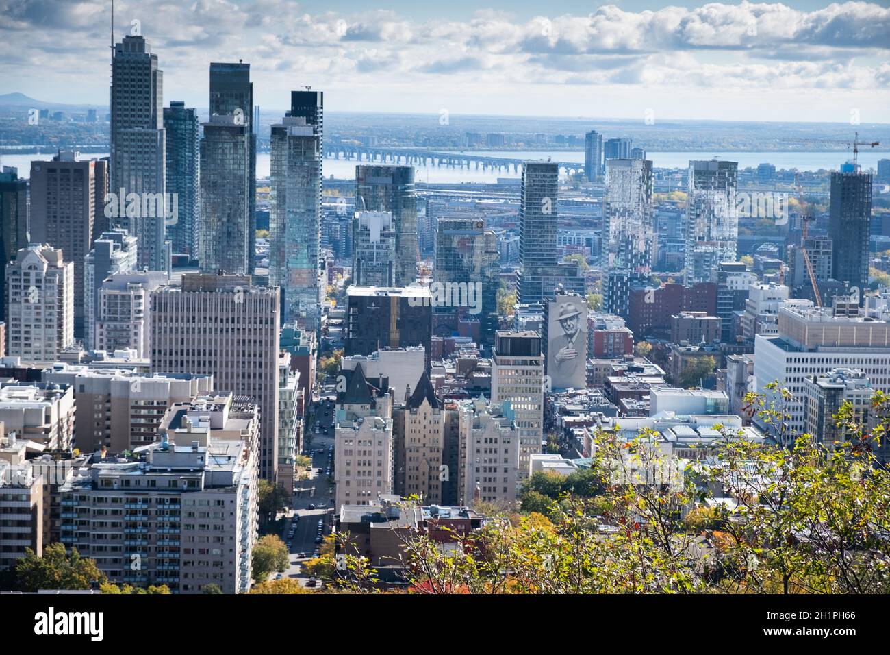 View of downtown Montreal from Mont Royal with mural of Montreal native Leonard Cohen and the Champlain Bridge over the St. Lawrence River. Stock Photo