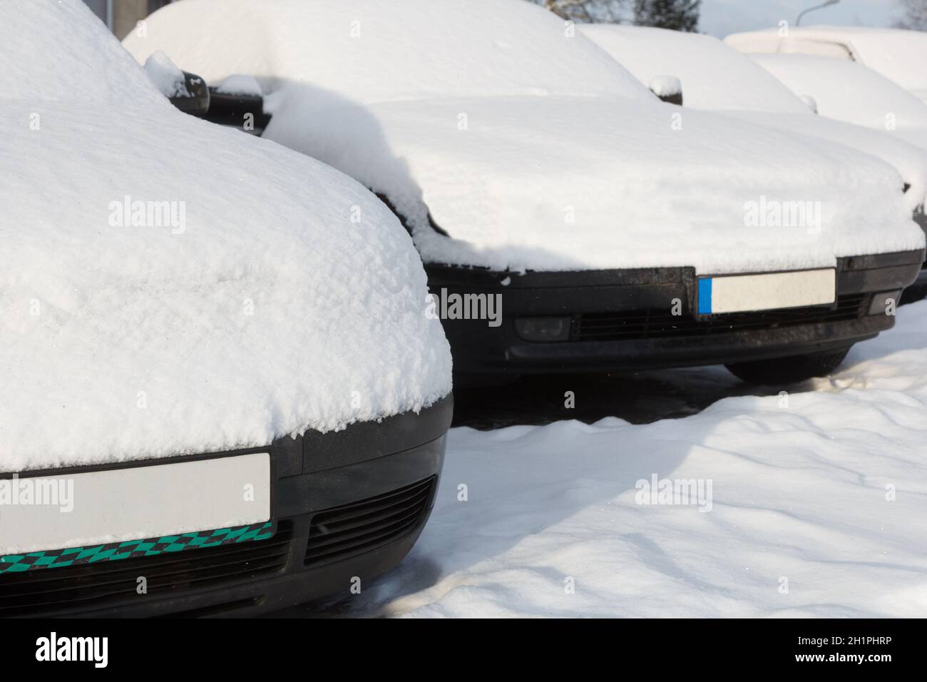 Snow covered cars parked in a row next to each other. Cars on the ...