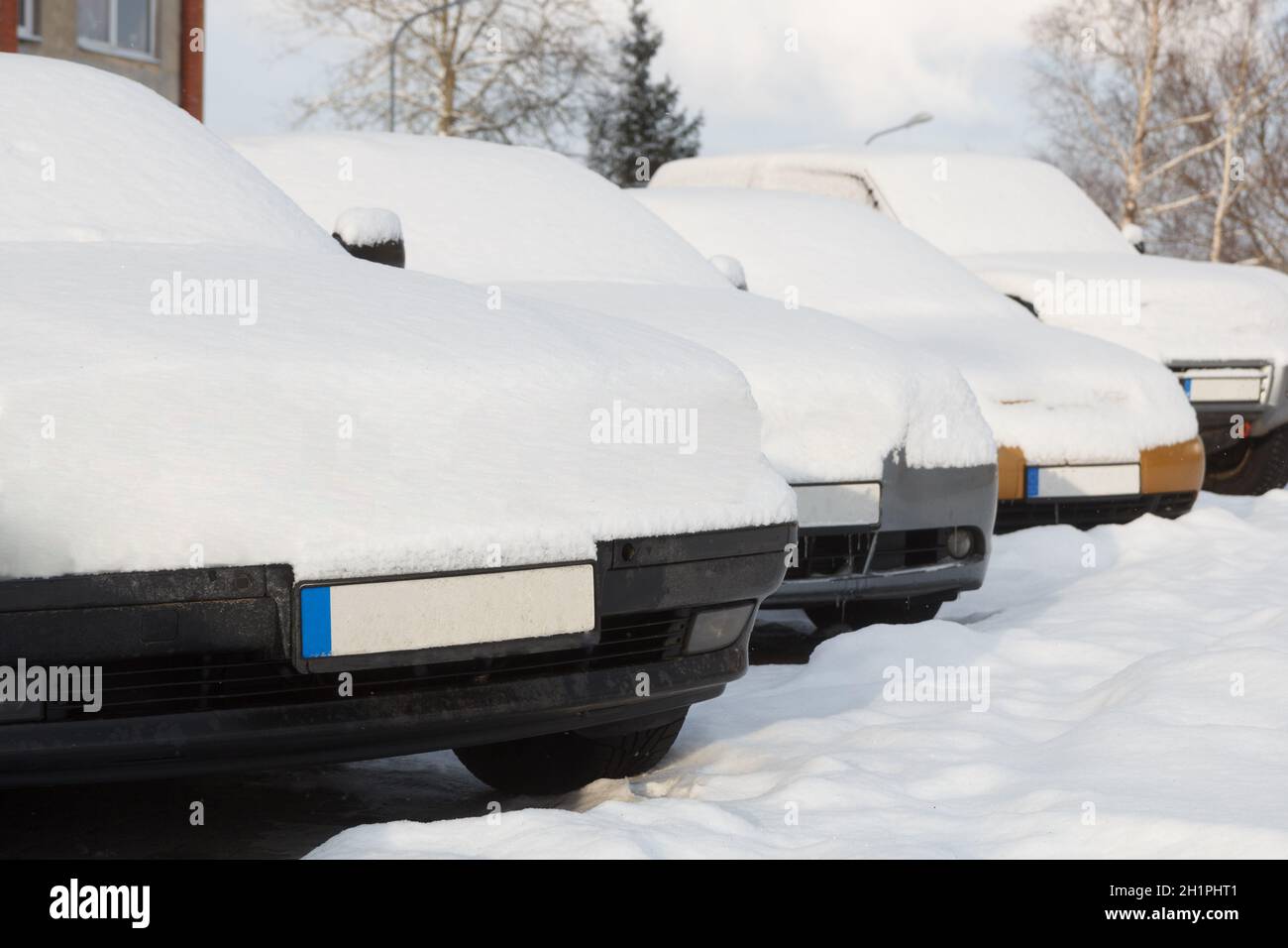 Snow covered cars parked in a row next to each other. Cars on the ...