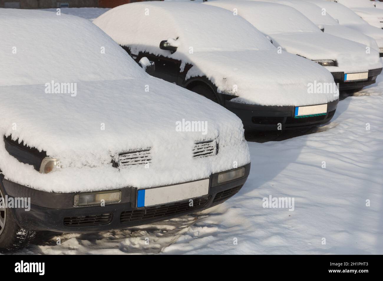 Snow covered cars parked in a row next to each other. Cars on the ...