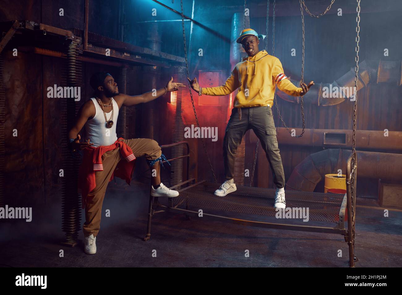 Two rappers posing, performing in cool studio, underground decoration. Hip-hop performers, trendy rap singers, break-dancers Stock Photo