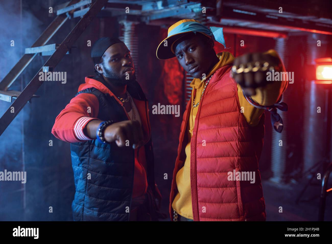 Rapper Using Things Two rappers with gold jewelry in cool studio, underground decoration ...