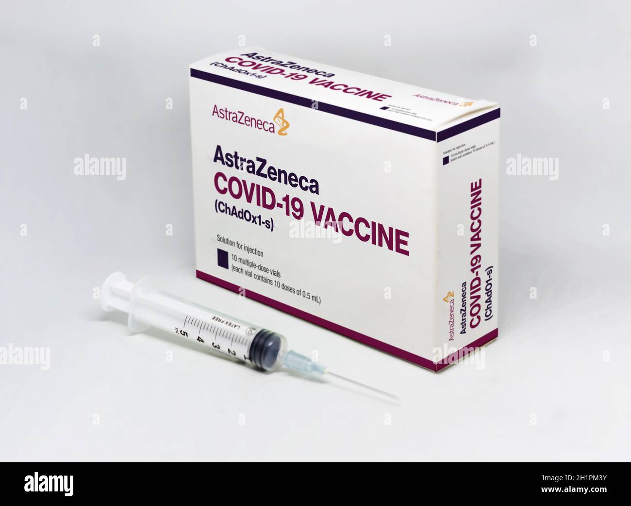 Cambridge, UK, february 5th 2021: A syringe next to the AstraZeneca Covid-19 vaccine box isolated on a white background. Health and prevention. Stock Photo