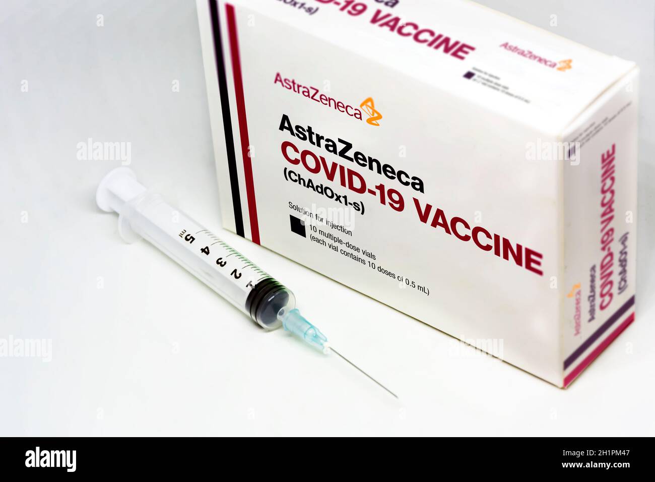 Cambridge, UK, february 5th 2021: A syringe next to the AstraZeneca Covid-19 vaccine box isolated on a white background. Health and prevention. Stock Photo