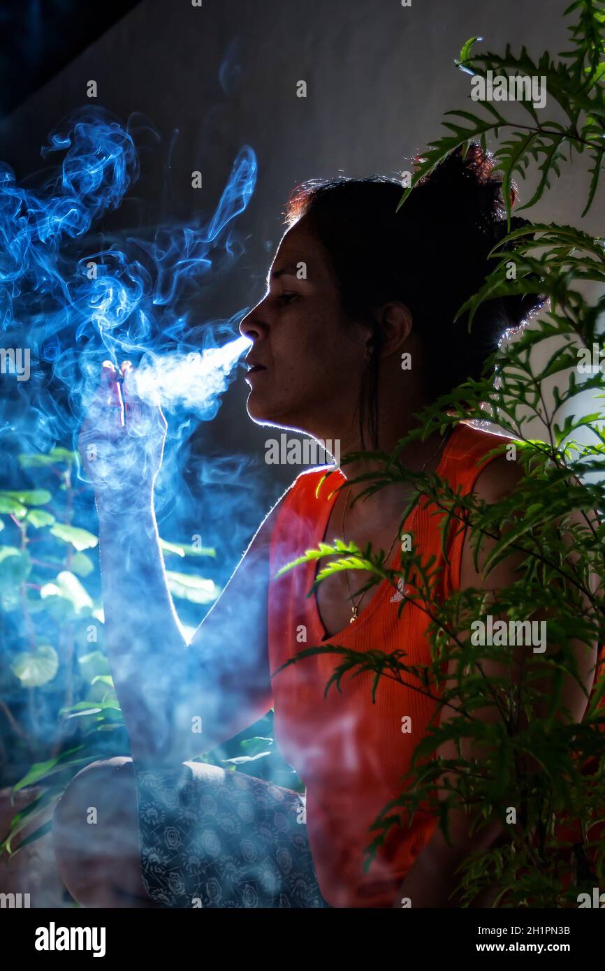 Woman smoking at night, exhaling a lot of smoke Stock Photo