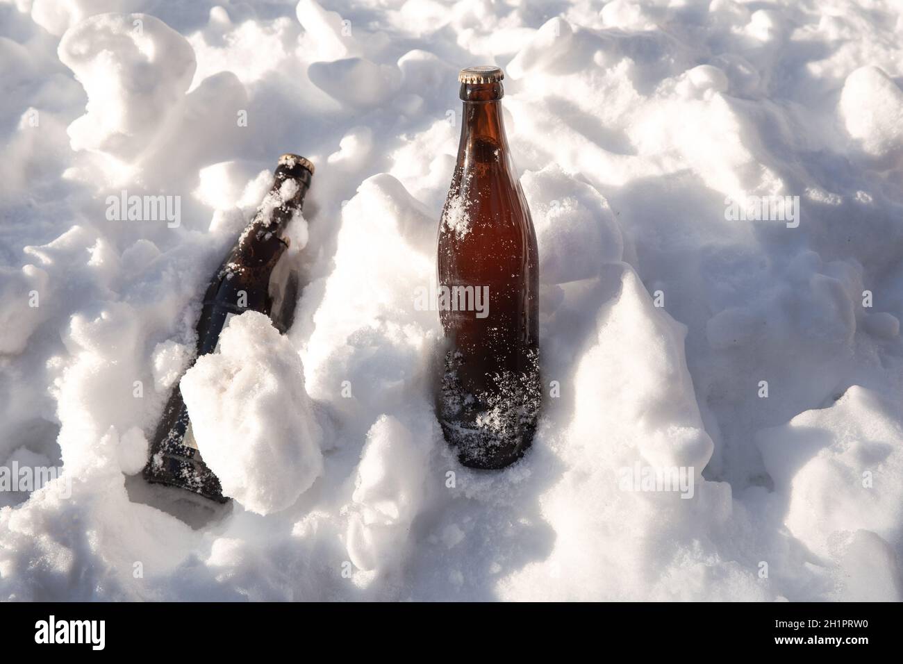 Two ice cold brown beer bottles in fresh white snow in the sun background, Winter,Snow,alcohol,drink concept copy space Stock Photo