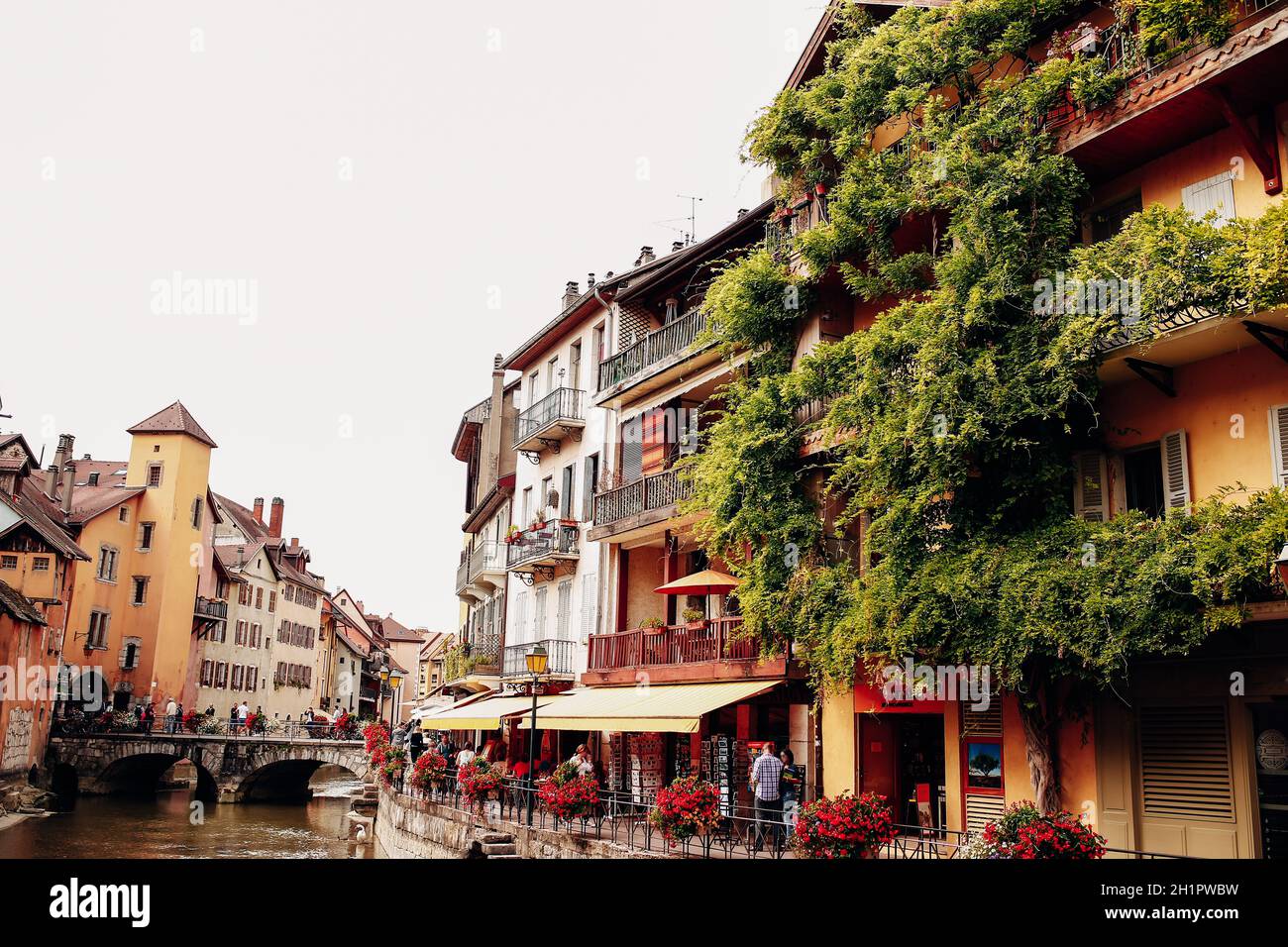 Annecy city water channel, red flowers, old buildings, bridge, green balconies. High quality photo Stock Photo